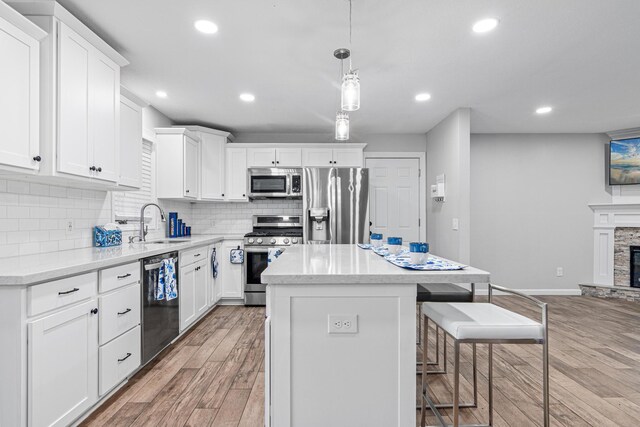 11508 Georgia Ave N, Champlin, MN 55316 - kitchen with stainless steel appliances, a sink, a kitchen island, a breakfast bar, and light wood finished floors