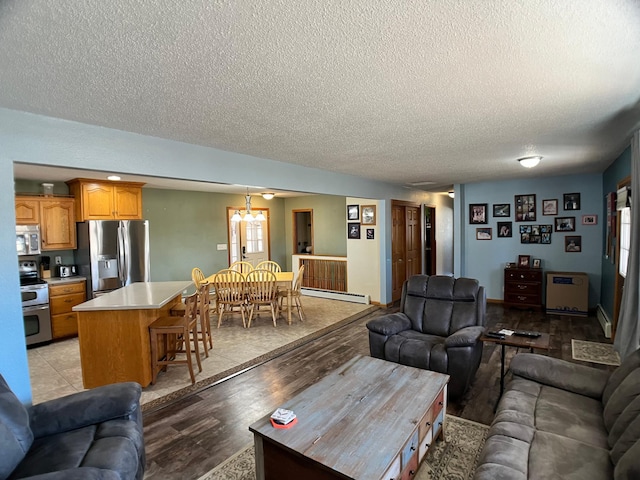 10306 Hemlock St NW, Annandale, MN 55302 - living area featuring a textured ceiling, a baseboard heating unit, light wood-type flooring, and a chandelier
