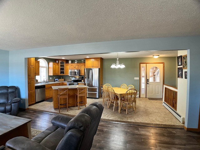 10306 Hemlock St NW, Annandale, MN 55302 - living room with a baseboard heating unit, a chandelier, a textured ceiling, wood finished floors, and baseboards