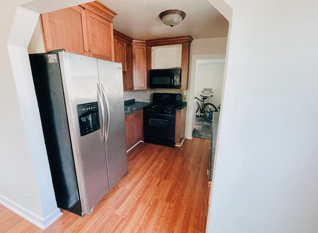 415 Francis St, Faribault, MN 55021 - kitchen featuring black appliances, light wood-type flooring, dark countertops, backsplash, and brown cabinetry