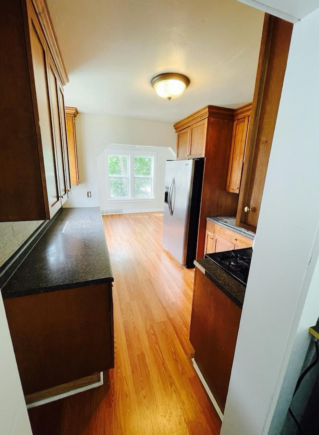 415 Francis St, Faribault, MN 55021 - kitchen with stainless steel refrigerator with ice dispenser, light wood finished floors, black gas cooktop, and dark stone counters