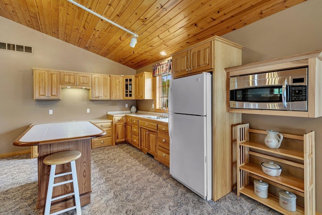 5386 165th St NE, Atwater, MN 56209 - kitchen featuring freestanding refrigerator, light colored carpet, stainless steel microwave, vaulted ceiling, and tile countertops