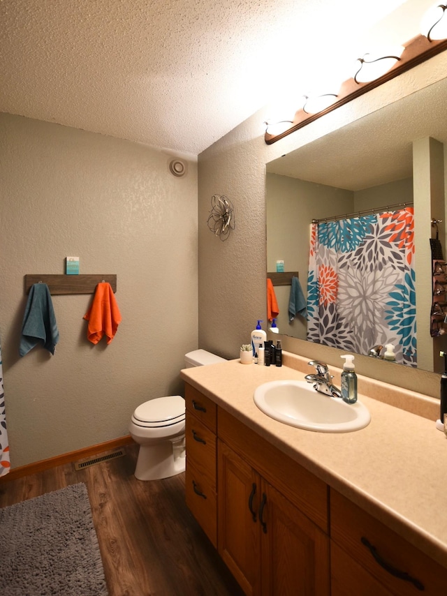 201 Ridge Dr, Kenyon, MN 55946 - bathroom featuring a textured wall, wood finished floors, vanity, toilet, and a textured ceiling