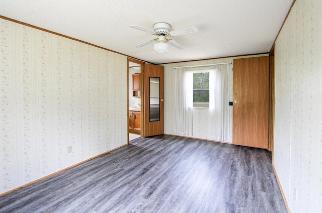 3146 Green Bay Rd, Sturgeon Lake, MN 55783 - empty room featuring dark wood-style floors, wallpapered walls, a textured ceiling, crown molding, and a ceiling fan