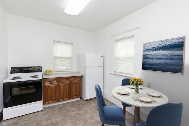 726 College St N, Fargo, ND 58102 - kitchen featuring freestanding refrigerator, electric range, brown cabinetry, and plenty of natural light