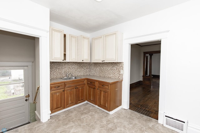 726 College St N, Fargo, ND 58102 - kitchen featuring a sink, decorative backsplash, baseboards, brown cabinetry, and cream cabinetry