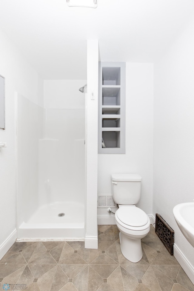 726 College St N, Fargo, ND 58102 - bathroom with baseboards, toilet, and a shower