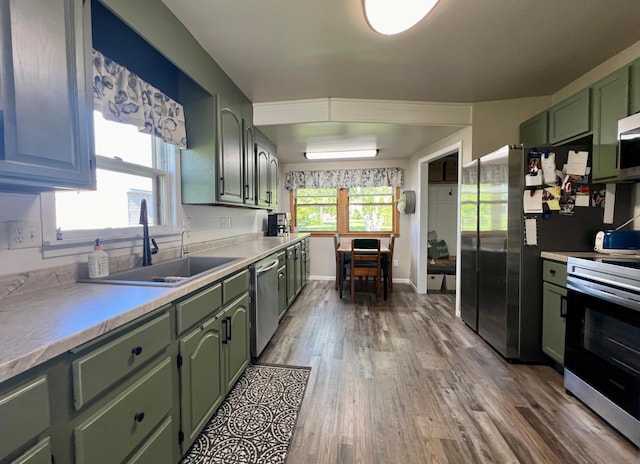 404 1st St S, Hoffman, MN 56339 - kitchen featuring green cabinetry, appliances with stainless steel finishes, wood finished floors, a sink, and light countertops