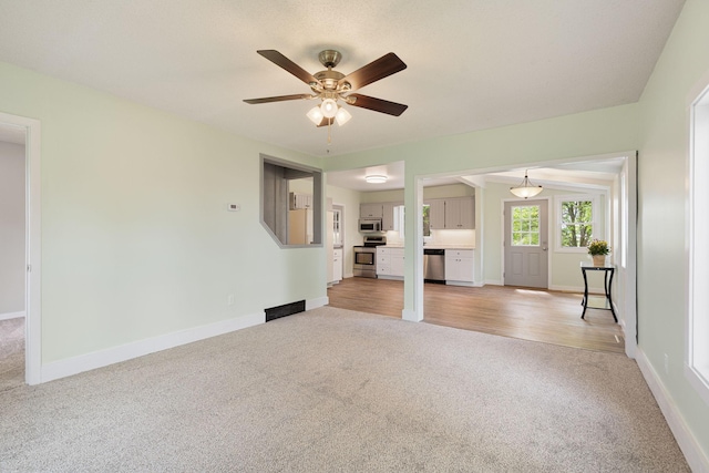 7149 92nd Ave SW, Lemond Twp, MN 56026 - unfurnished living room with light carpet, a ceiling fan, and baseboards