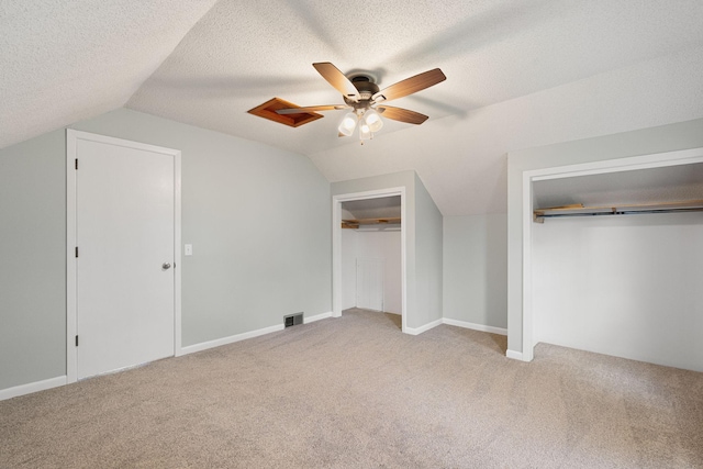 7149 92nd Ave SW, Lemond Twp, MN 56026 - unfurnished bedroom with multiple closets, carpet floors, lofted ceiling, ceiling fan, and a textured ceiling