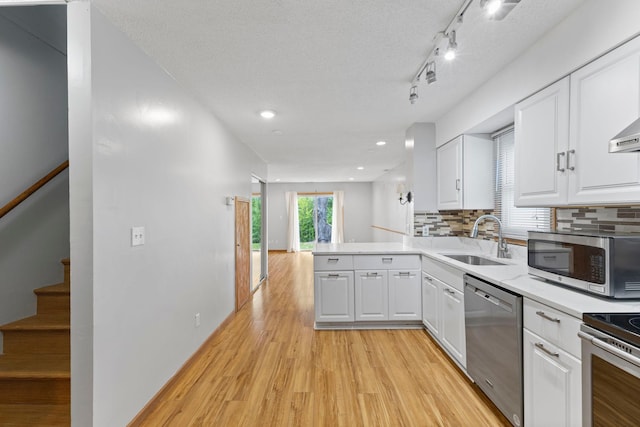 832 Woodgate Dr Unit 107, Vadnais Heights, MN 55127 - kitchen featuring appliances with stainless steel finishes, a sink, light wood-style flooring, a peninsula, and white cabinets