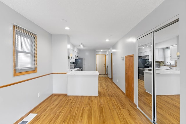 832 Woodgate Dr Unit 107, Vadnais Heights, MN 55127 - kitchen featuring freestanding refrigerator, light wood finished floors, white cabinetry, light countertops, and a peninsula