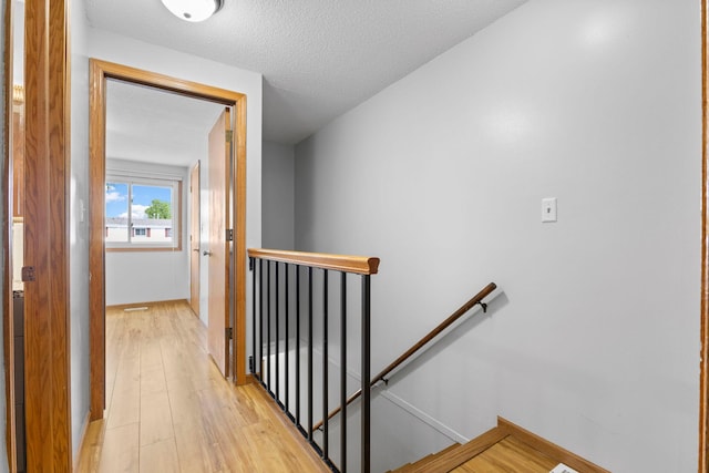 832 Woodgate Dr Unit 107, Vadnais Heights, MN 55127 - hallway featuring an upstairs landing, light wood-type flooring, baseboards, and a textured ceiling