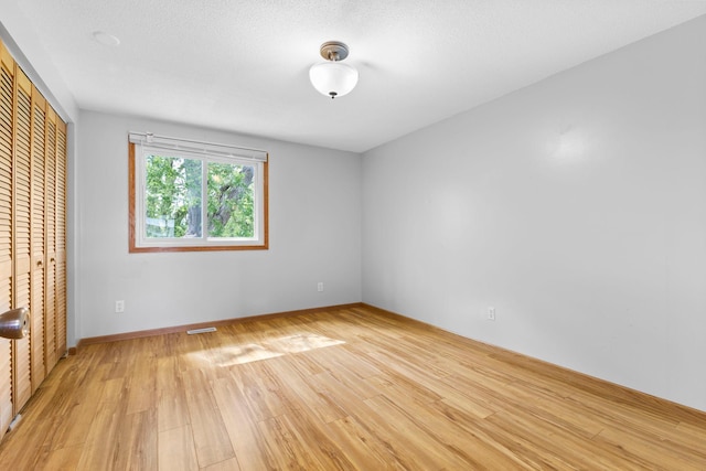 832 Woodgate Dr Unit 107, Vadnais Heights, MN 55127 - unfurnished bedroom with light wood finished floors, a closet, and baseboards