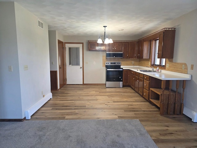 405 16th Ave NE, Waseca, MN 56093 - kitchen with stainless steel range with electric cooktop, a baseboard radiator, a sink, extractor fan, and a chandelier