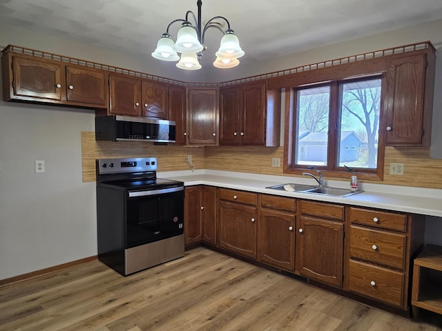 405 16th Ave NE, Waseca, MN 56093 - kitchen with appliances with stainless steel finishes, a sink, a chandelier, light countertops, and backsplash