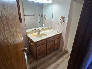 405 16th Ave NE, Waseca, MN 56093 - bathroom featuring tile walls, vanity, wood finished floors, and wainscoting