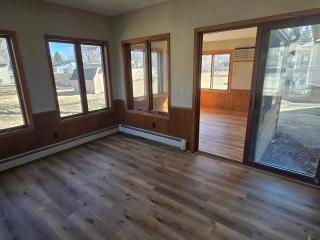 405 16th Ave NE, Waseca, MN 56093 - unfurnished sunroom with wood finished floors, a baseboard heating unit, and wainscoting
