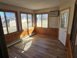 405 16th Ave NE, Waseca, MN 56093 - unfurnished sunroom featuring a baseboard radiator, wood finished floors, an AC wall unit, wood walls, and wainscoting