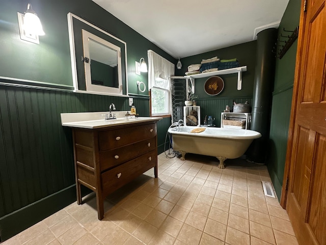 40580 Bow Trl, Nerstrand, MN 55053 - full bathroom featuring wainscoting, vanity, a soaking tub, tile patterned floors, and a wood stove