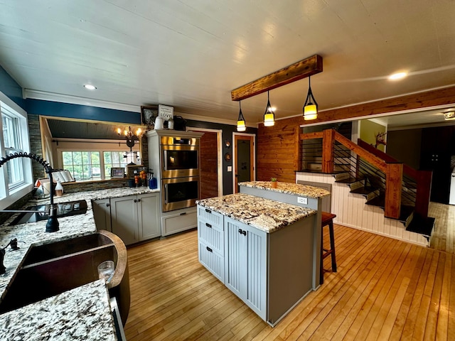 40580 Bow Trl, Nerstrand, MN 55053 - kitchen featuring stainless steel double oven, light wood-style flooring, a kitchen island, light stone counters, and recessed lighting