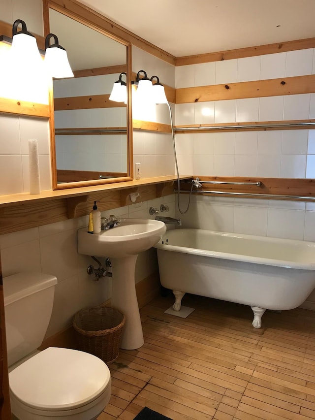 35379 215th Ave, Eagle Valley Twp, MN 56440 - full bathroom featuring tile walls, a freestanding tub, toilet, wood-type flooring, and a sink