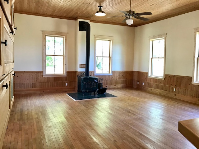 35379 215th Ave, Eagle Valley Twp, MN 56440 - unfurnished living room featuring a wainscoted wall, wooden walls, a wood stove, light wood finished floors, and ornamental molding