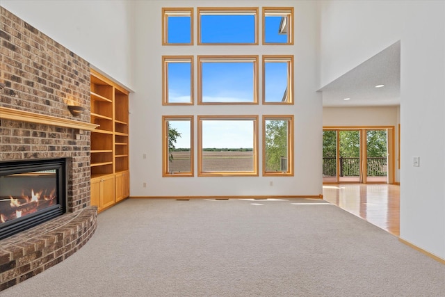 27285 Cambodia Ave, Castle Rock Twp, MN 55024 - unfurnished living room featuring carpet flooring, a high ceiling, baseboards, a brick fireplace, and built in features