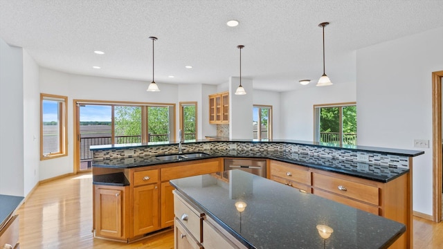 27285 Cambodia Ave, Castle Rock Twp, MN 55024 - kitchen featuring a sink, a kitchen island, light wood-style floors, dishwasher, and a textured ceiling