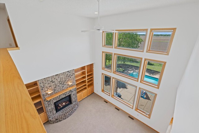 27285 Cambodia Ave, Castle Rock Twp, MN 55024 - unfurnished living room featuring a fireplace, built in shelves, carpet floors, a towering ceiling, and a ceiling fan
