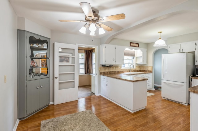 613 9th St NW, Faribault, MN 55021 - kitchen featuring freestanding refrigerator, a ceiling fan, a peninsula, white cabinetry, and light wood-type flooring