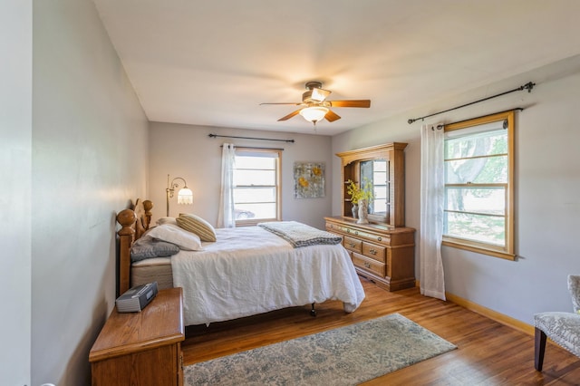 613 9th St NW, Faribault, MN 55021 - bedroom with multiple windows, wood finished floors, baseboards, and a ceiling fan