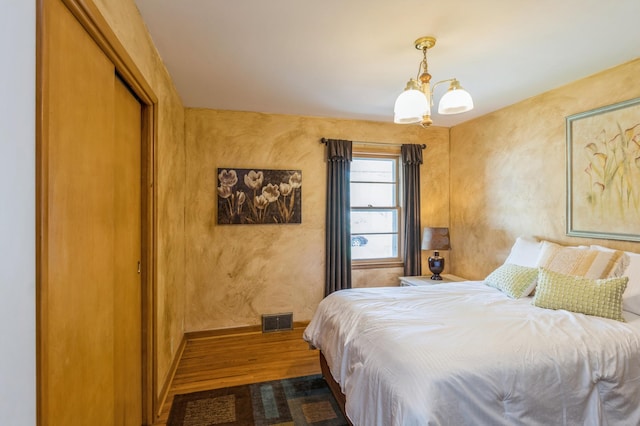 613 9th St NW, Faribault, MN 55021 - bedroom with wood finished floors, a chandelier, baseboards, and a closet