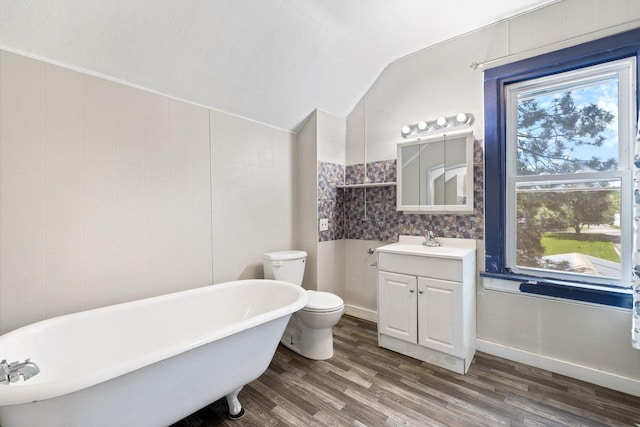 202 6th Ave, Bovey, MN 55709 - full bathroom featuring a freestanding tub, vanity, vaulted ceiling, wood finished floors, and toilet