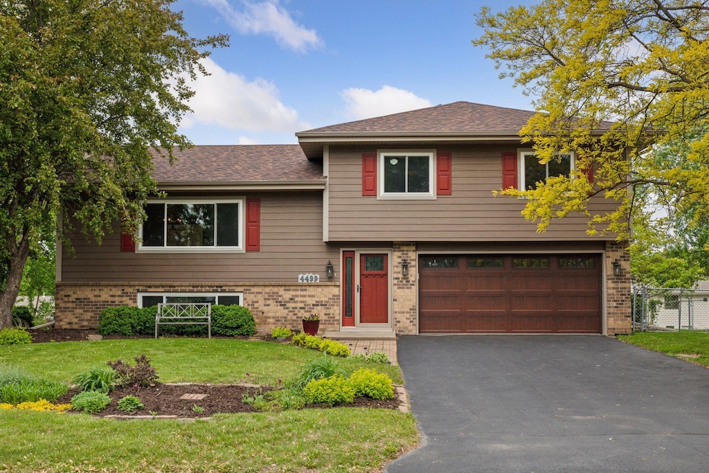 4499 Oakhurst Ave, Vadnais Heights, MN 55127 - tri-level home with brick siding, a garage, driveway, and a shingled roof