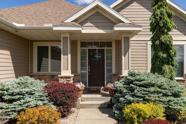 1121 Maplebeck Enclave NE, Byron, MN 55920 - property entrance with a shingled roof, stone siding, and covered porch