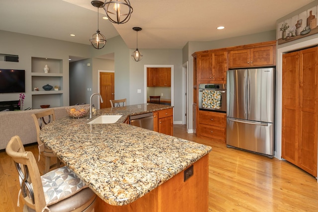 1121 Maplebeck Enclave NE, Byron, MN 55920 - kitchen with appliances with stainless steel finishes, a sink, light wood-style floors, built in features, and brown cabinets