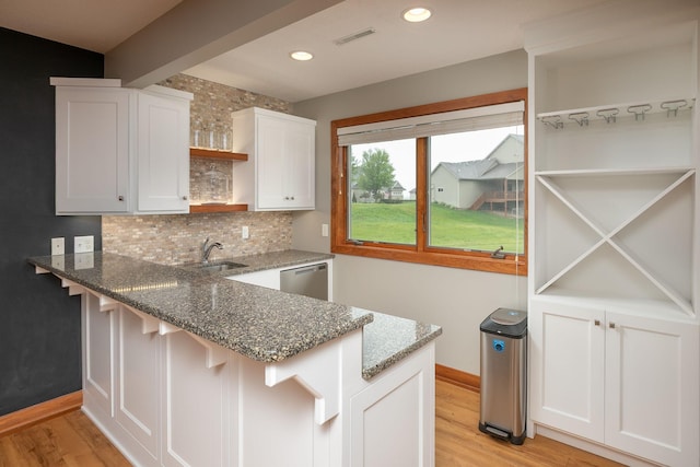 1121 Maplebeck Enclave NE, Byron, MN 55920 - kitchen with open shelves, baseboards, dark stone countertops, stainless steel dishwasher, and a peninsula