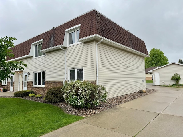 1815 Lakewood Ave, Albert Lea, MN 56007 - view of side of property featuring roof with shingles, mansard roof, a lawn, and brick siding