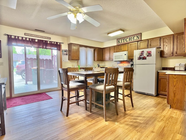 1815 Lakewood Ave, Albert Lea, MN 56007 - kitchen featuring white appliances, light wood-type flooring, a textured ceiling, a ceiling fan, and brown cabinetry