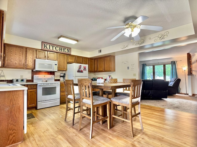 1815 Lakewood Ave, Albert Lea, MN 56007 - kitchen with white appliances, a textured ceiling, brown cabinetry, light wood-style flooring, and ceiling fan