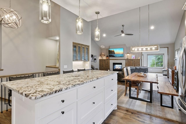 525 Roanoke Ct, Waconia, MN 55387 - kitchen with a glass covered fireplace, ceiling fan, light stone countertops, dark wood finished floors, and high vaulted ceiling