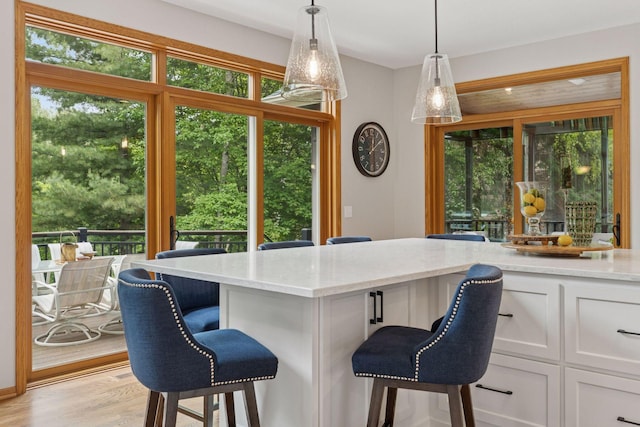 18172 Tamarack Dr, Minnetonka, MN 55345 - kitchen with a breakfast bar, white cabinetry, light stone countertops, and pendant lighting