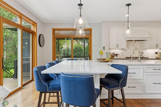 18172 Tamarack Dr, Minnetonka, MN 55345 - kitchen with decorative backsplash, light stone countertops, light wood-style flooring, and white cabinets