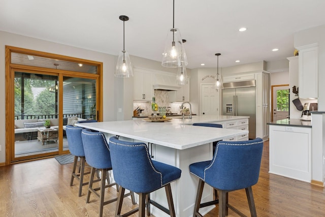 18172 Tamarack Dr, Minnetonka, MN 55345 - kitchen featuring stainless steel built in refrigerator, a spacious island, tasteful backsplash, white cabinets, and light wood finished floors