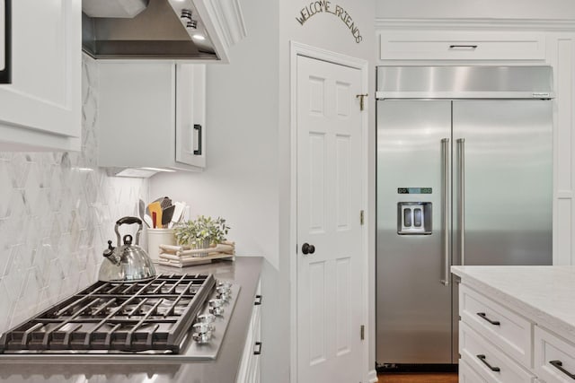 18172 Tamarack Dr, Minnetonka, MN 55345 - kitchen with appliances with stainless steel finishes, extractor fan, decorative backsplash, and white cabinets