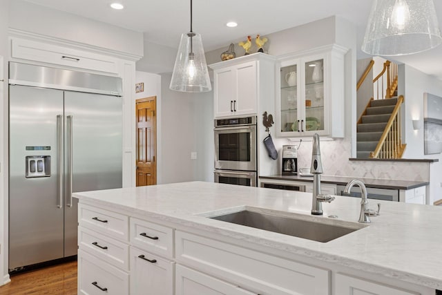 18172 Tamarack Dr, Minnetonka, MN 55345 - kitchen with appliances with stainless steel finishes, white cabinets, decorative backsplash, glass insert cabinets, and light stone counters