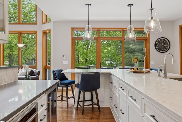 18172 Tamarack Dr, Minnetonka, MN 55345 - kitchen featuring a sink, dark wood-style flooring, white cabinetry, beverage cooler, and hanging light fixtures