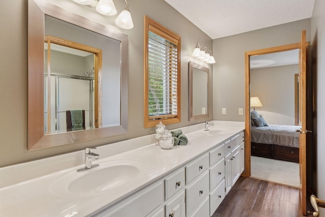 18172 Tamarack Dr, Minnetonka, MN 55345 - ensuite bathroom with double vanity, wood finished floors, a textured ceiling, and an enclosed shower