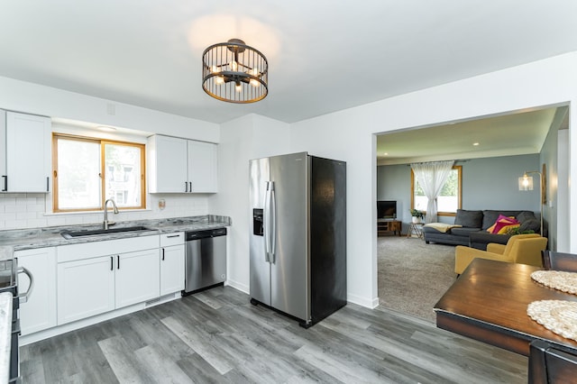 311 Wisconsin St, Lake City, MN 55041 - kitchen featuring appliances with stainless steel finishes, a sink, white cabinets, decorative backsplash, and wood finished floors